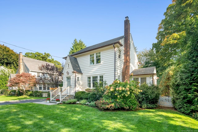 view of front of property with a shingled roof, fence, a chimney, and a front lawn