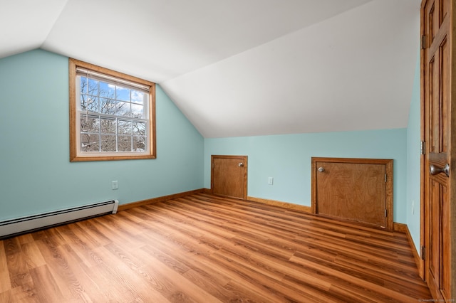 bonus room with light hardwood / wood-style flooring, vaulted ceiling, and a baseboard heating unit