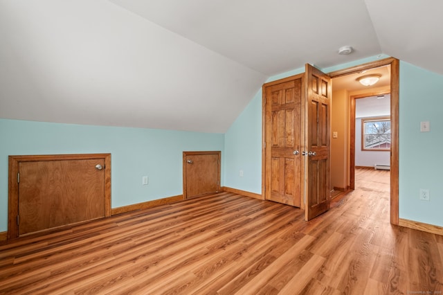 bonus room featuring light wood-type flooring, vaulted ceiling, and a baseboard heating unit