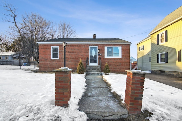 bungalow-style house featuring a chimney, fence, and brick siding