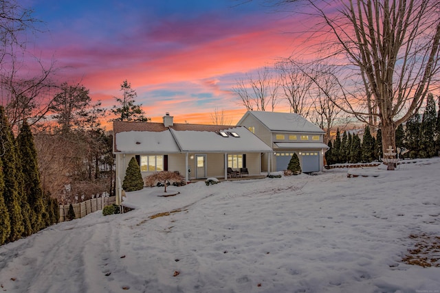 snow covered property featuring a garage and a chimney