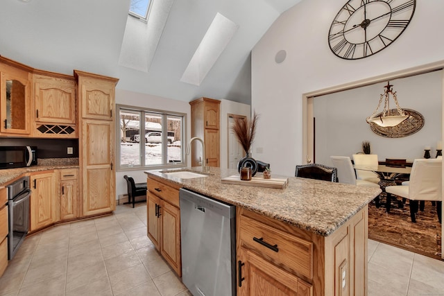 kitchen featuring a skylight, light tile patterned floors, an island with sink, stainless steel appliances, and a sink