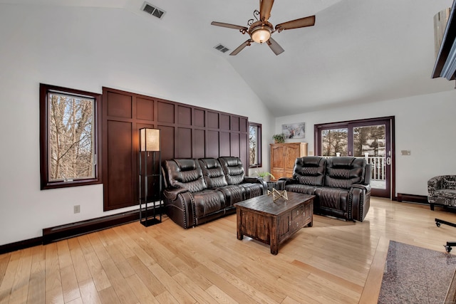 living area featuring ceiling fan, high vaulted ceiling, light wood finished floors, and visible vents