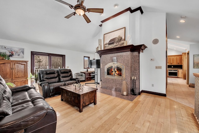 living area with ceiling fan, a tile fireplace, recessed lighting, baseboards, and light wood-type flooring