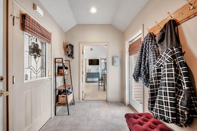 foyer featuring lofted ceiling, light tile patterned floors, and baseboards