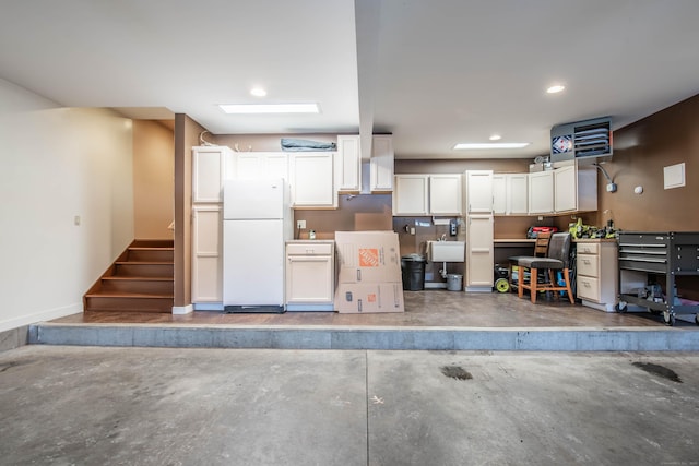 garage featuring recessed lighting, baseboards, a sink, and freestanding refrigerator