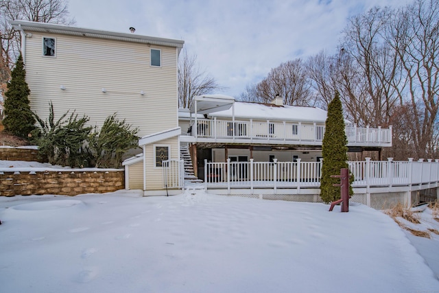 snow covered house with a wooden deck and stairs