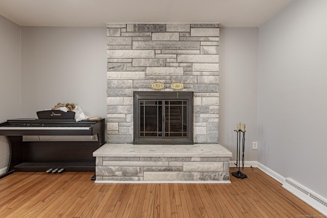 details featuring hardwood / wood-style flooring, a stone fireplace, and a baseboard radiator