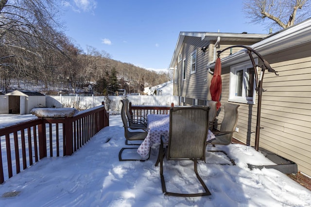 snow covered patio with a deck and a storage shed