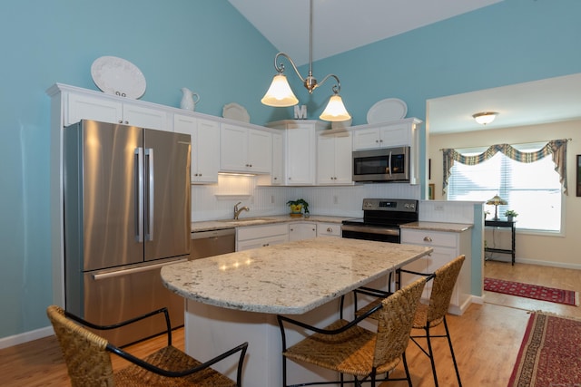 kitchen with appliances with stainless steel finishes, white cabinetry, and a center island