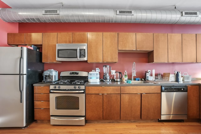 kitchen with visible vents, appliances with stainless steel finishes, brown cabinets, and a sink