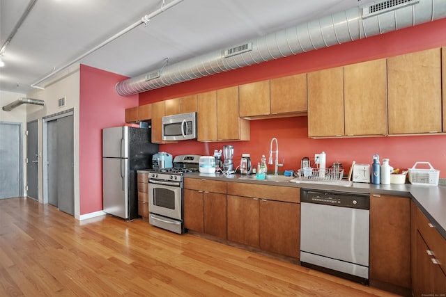 kitchen featuring a sink, visible vents, appliances with stainless steel finishes, light wood-type flooring, and brown cabinets