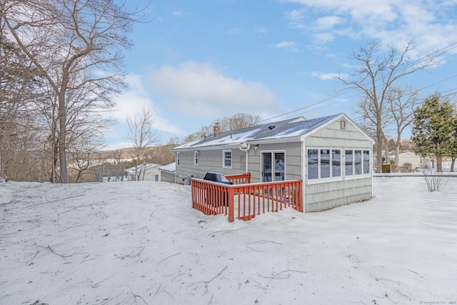 snow covered property featuring a chimney and a wooden deck