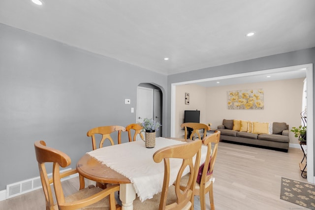 dining area with arched walkways, baseboards, light wood-style flooring, and recessed lighting