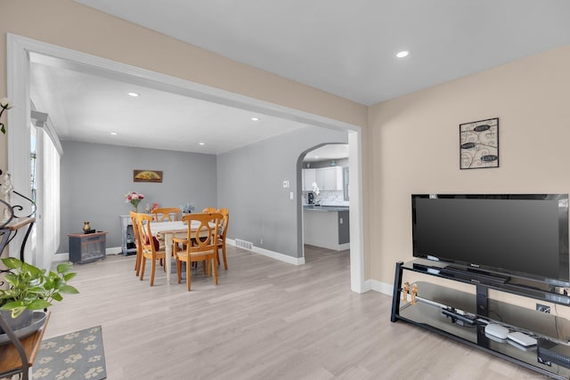 dining area with arched walkways, wood finished floors, visible vents, and baseboards