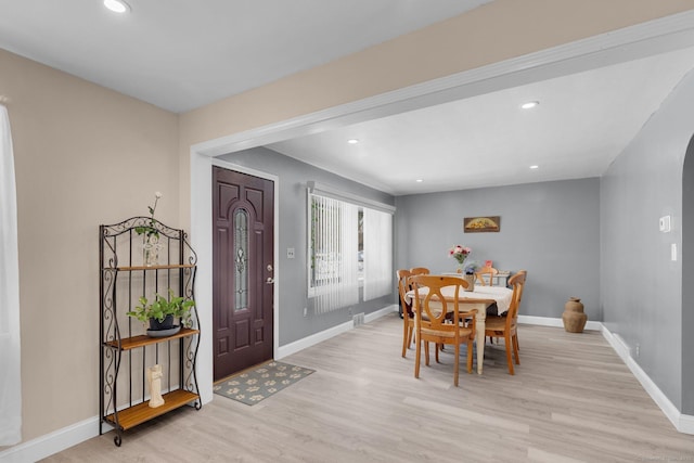 dining area featuring arched walkways, recessed lighting, baseboards, and light wood-style floors