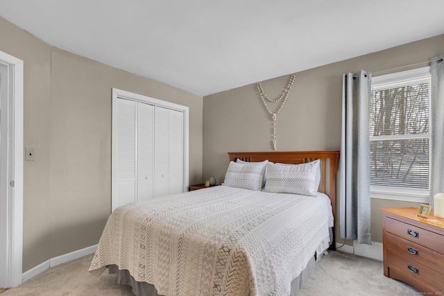 bedroom featuring a closet, light carpet, and baseboards