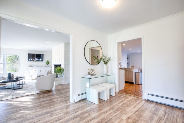 corridor with light hardwood / wood-style flooring, crown molding, and a baseboard heating unit