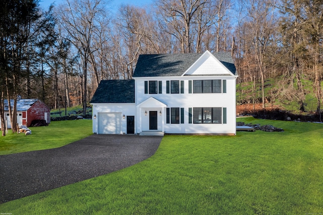 view of front facade with a garage, aphalt driveway, and a front lawn