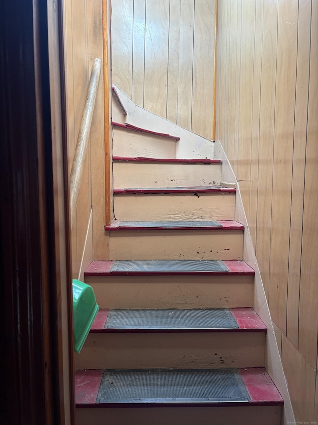 staircase featuring wood walls