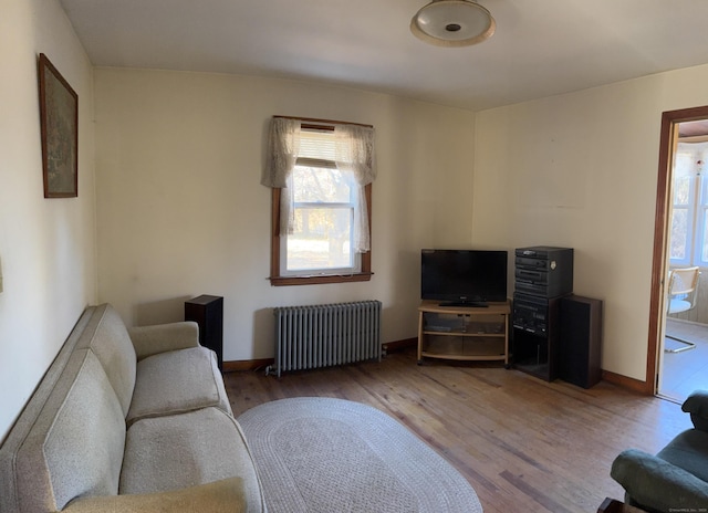 living room featuring baseboards, wood finished floors, and radiator heating unit