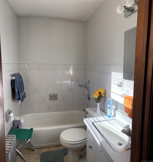 bathroom with radiator, toilet, vanity, a bathtub, and tile walls