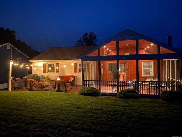 back of house at night with a lawn and a patio