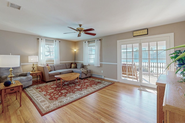 living room with visible vents, light wood-style flooring, baseboard heating, a ceiling fan, and baseboards