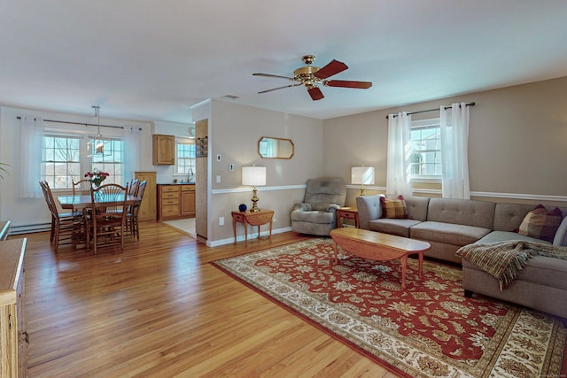 living area with visible vents, ceiling fan, light wood-style flooring, and baseboards