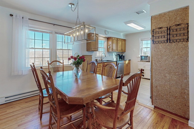 dining area featuring a baseboard heating unit, light wood-type flooring, a healthy amount of sunlight, and visible vents