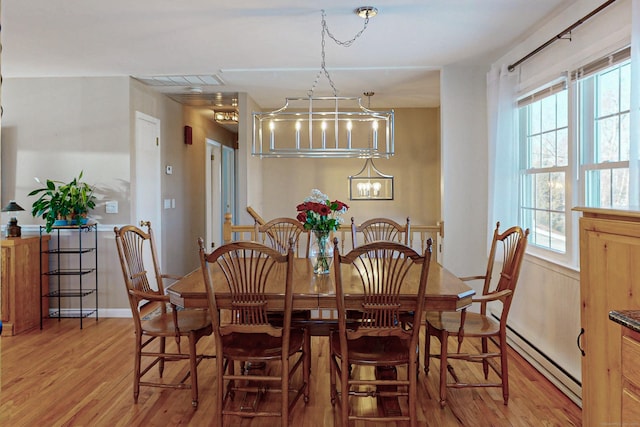 dining space with a baseboard heating unit and wood finished floors