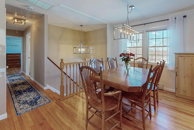 dining space with an inviting chandelier, attic access, baseboards, and light wood finished floors