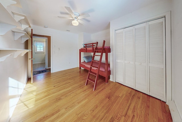 bedroom with light wood finished floors, visible vents, a ceiling fan, and a closet