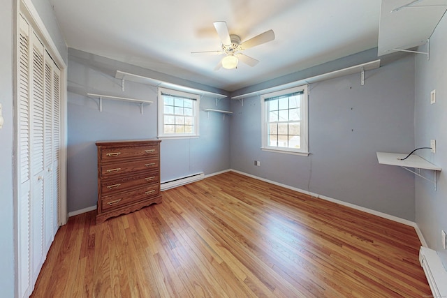 unfurnished bedroom with a baseboard heating unit, light wood-style floors, baseboards, and ceiling fan