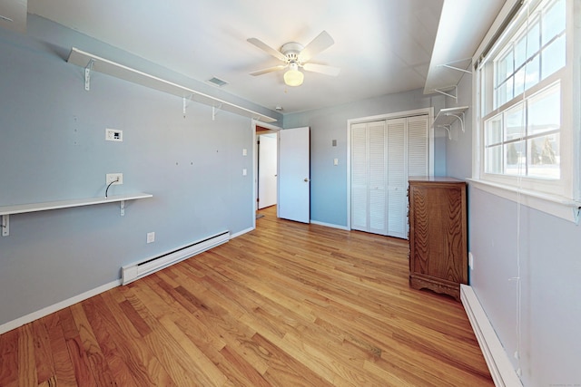 unfurnished bedroom featuring light wood finished floors, baseboards, and a baseboard heating unit