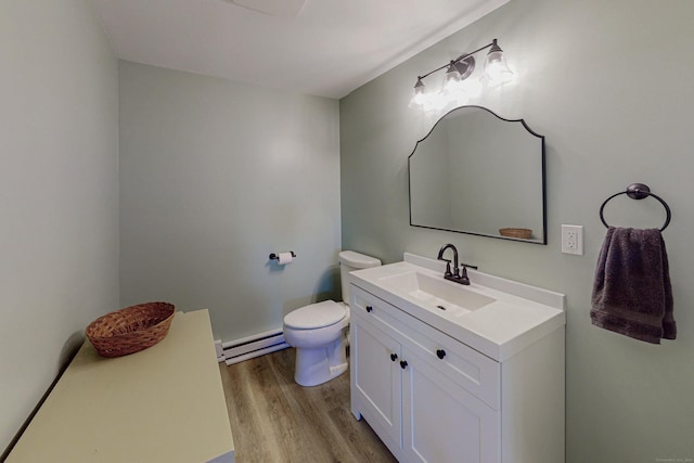 bathroom with vanity, baseboard heating, wood finished floors, and toilet