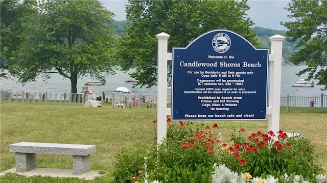 community / neighborhood sign with a lawn and fence