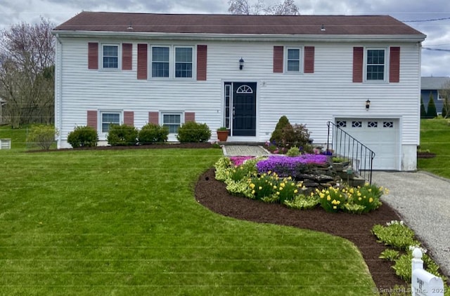 raised ranch with a front yard, driveway, and an attached garage