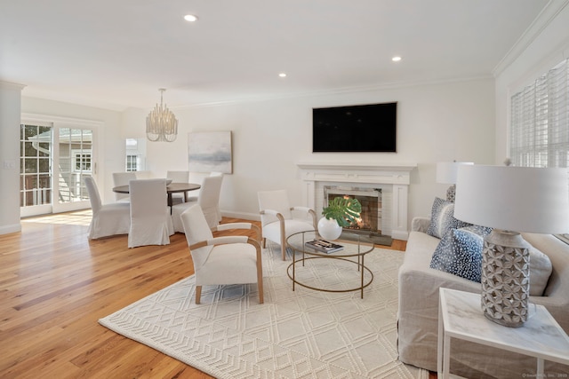 living area featuring ornamental molding, a warm lit fireplace, wood finished floors, recessed lighting, and an inviting chandelier