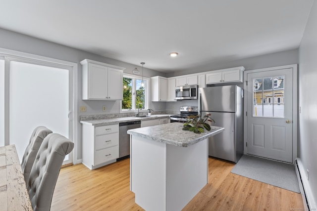 kitchen with white cabinetry, stainless steel appliances, a kitchen island, baseboard heating, and pendant lighting