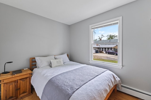 bedroom featuring wood-type flooring and a baseboard heating unit