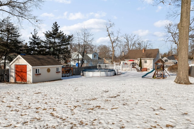 snowy yard with an outbuilding, a playground, a residential view, and a covered pool