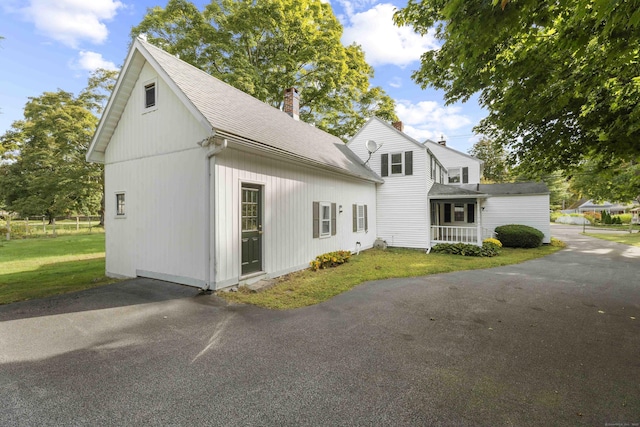 view of front of property featuring a shingled roof, a chimney, and a front lawn