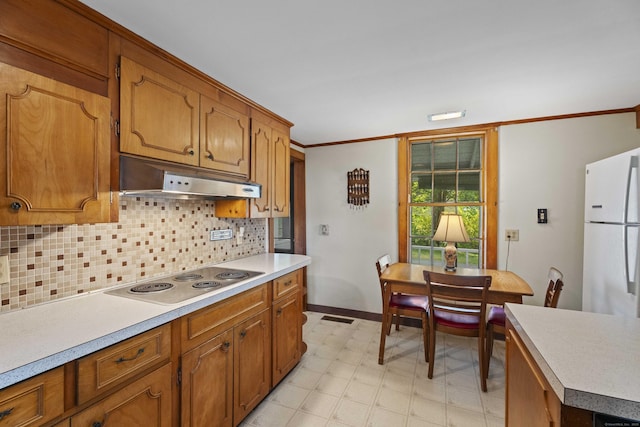 kitchen with light floors, freestanding refrigerator, light countertops, stainless steel electric cooktop, and under cabinet range hood