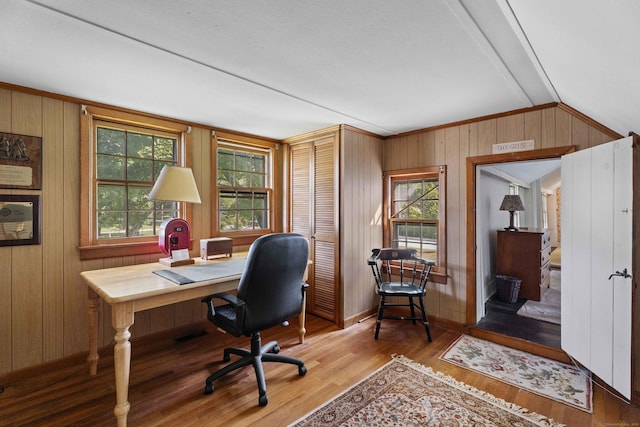 home office featuring vaulted ceiling, wood walls, plenty of natural light, and wood finished floors