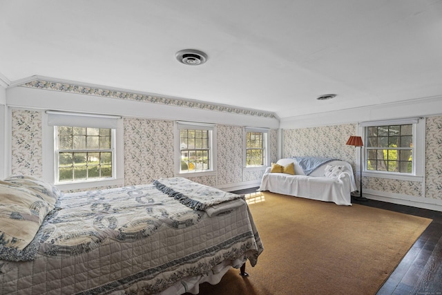 bedroom with wallpapered walls, multiple windows, baseboards, and wood finished floors