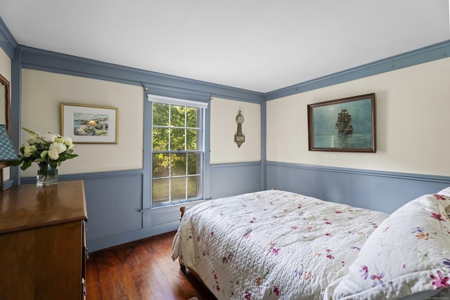 bedroom featuring a wainscoted wall and dark wood-style floors