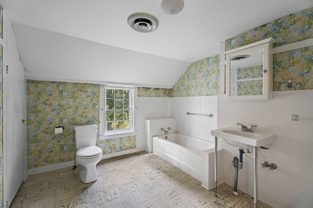 full bathroom with lofted ceiling, a bath, and wallpapered walls