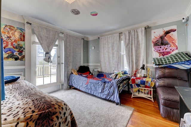 bedroom with access to exterior, crown molding, and wood finished floors