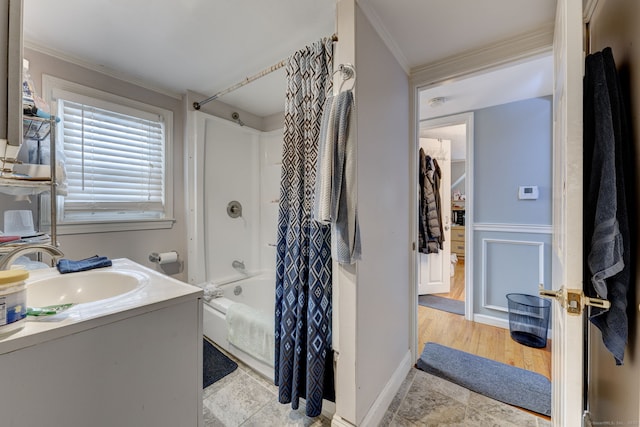 full bath with ornamental molding, shower / bath combo with shower curtain, vanity, and a decorative wall